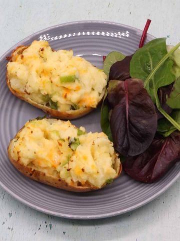 Cheese and spring onion baked potato on grey plate with salad leaves