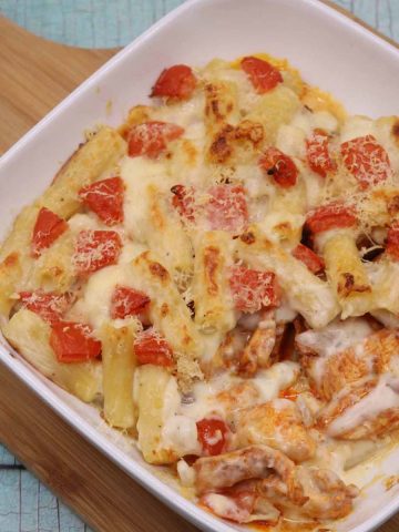 Chicken pasta bake in square oven dish on wooden board