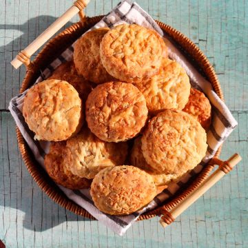 a stack of Chilli Cheese scones in a bread basket sitting on black and white towel