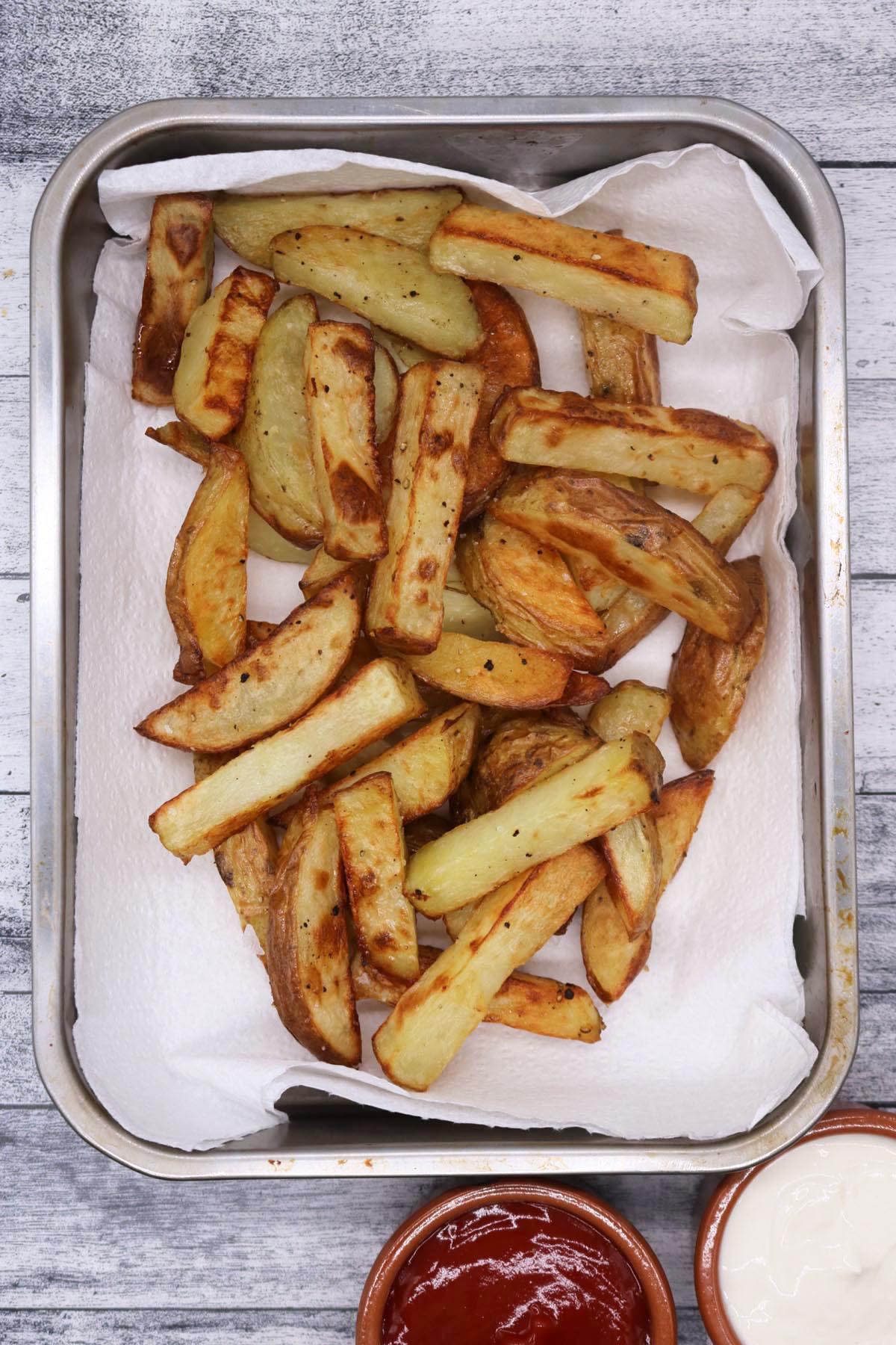 chunky oven chips on kitchen towel in a rectangle oven tray