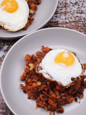 Corned beef hash in grey bowl with fried egg on top