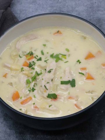 Creamy chicken and vegetable soup in bowl topped with parsley