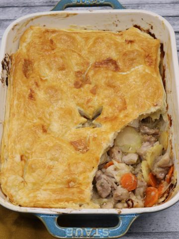 Easy chicken and vegetable pie in large rectangle oven dish with slice removed