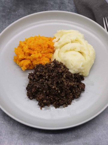Haggis on grey plate with mashed potatoes and carrot and swede mash
