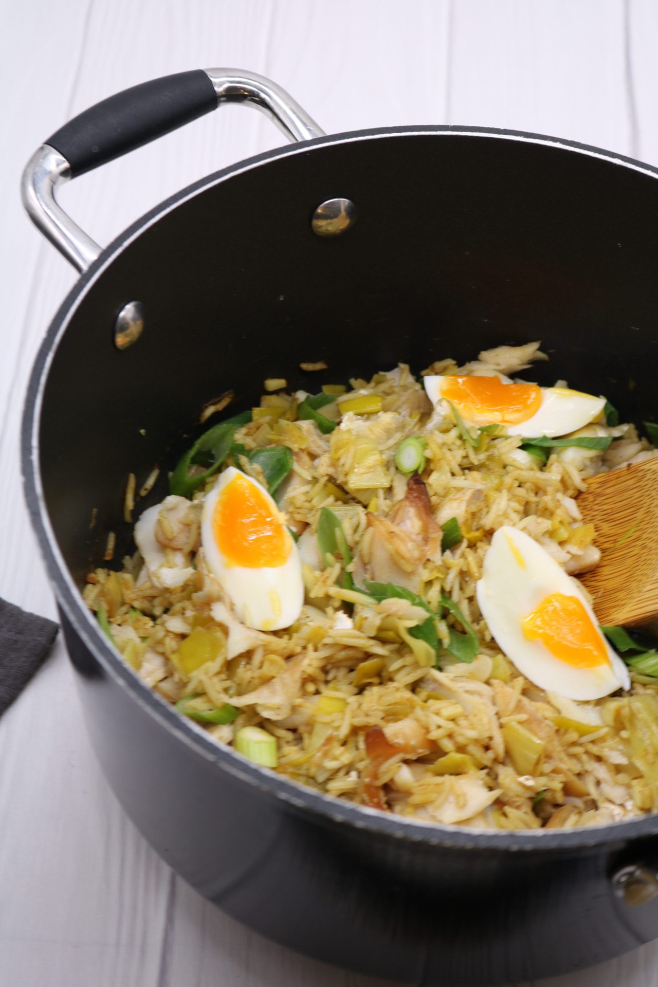 Kedgeree in large pan with wooded spoon
