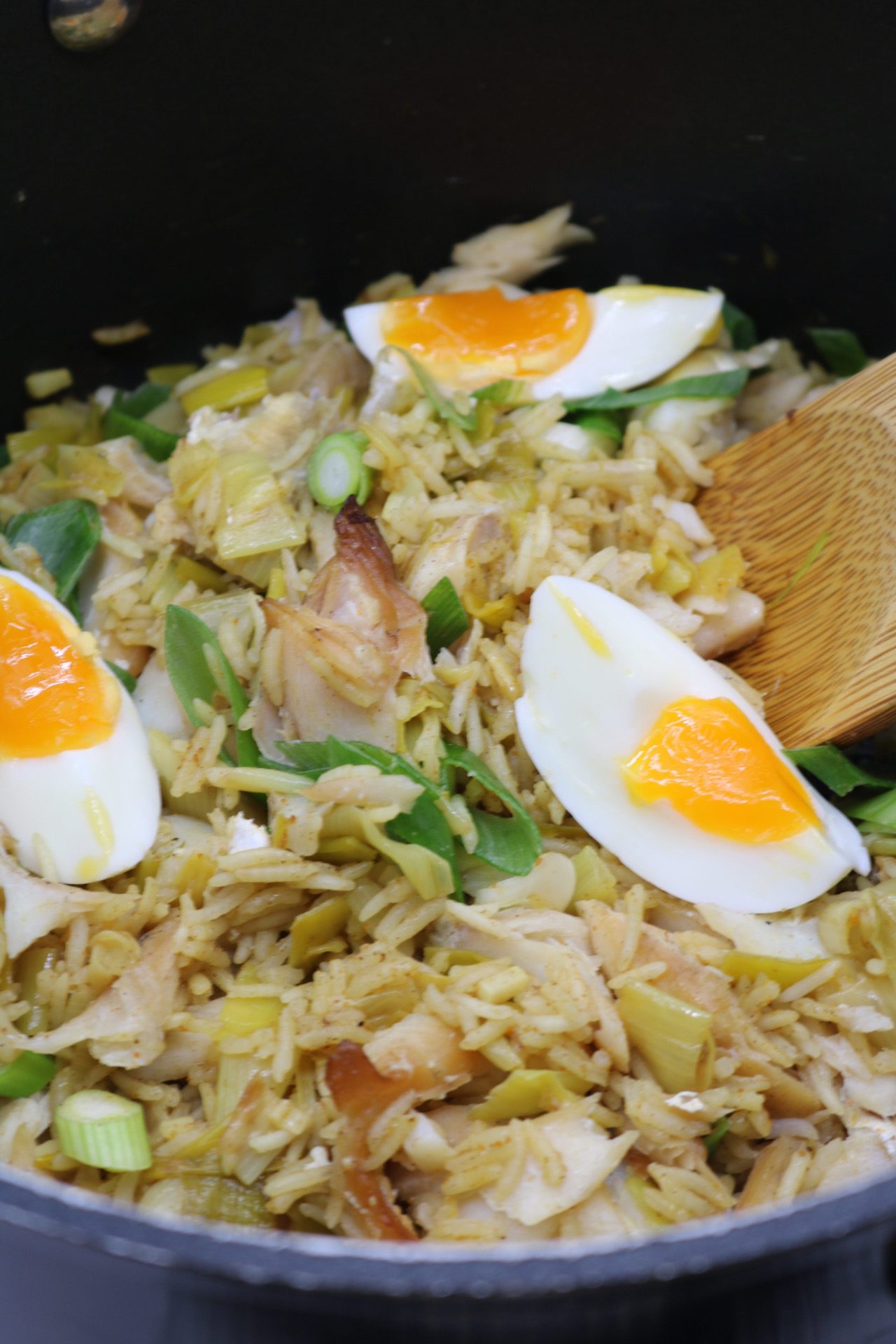 Kedgeree in large pan with wooded spoon