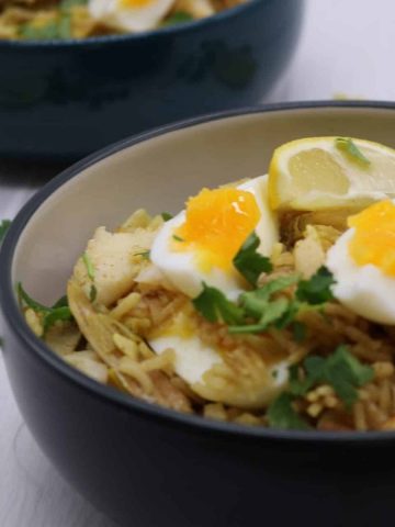 Kedgeree in two bowls with wedges of lemon and soft boiled egg