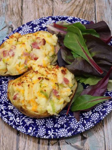 leek and bacon baked potato on blue and white plate with salad leaves