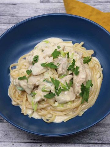 creamy chicken linguine in blue bowl with yellow napkin at the side