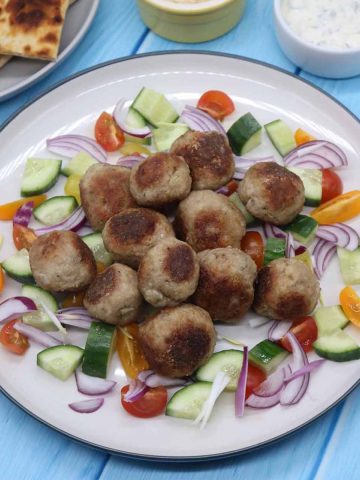 Meze meatbals in plate with onion, cucumber and tomatoes.