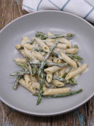 penne pasta with asparagus in gorgonzola sauce in grey bowl