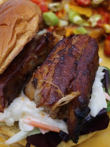 Pork belly slices in bun with coleslaw and salad leaves