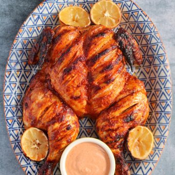 portuguese chicken on large oval serving dish with lemon halves