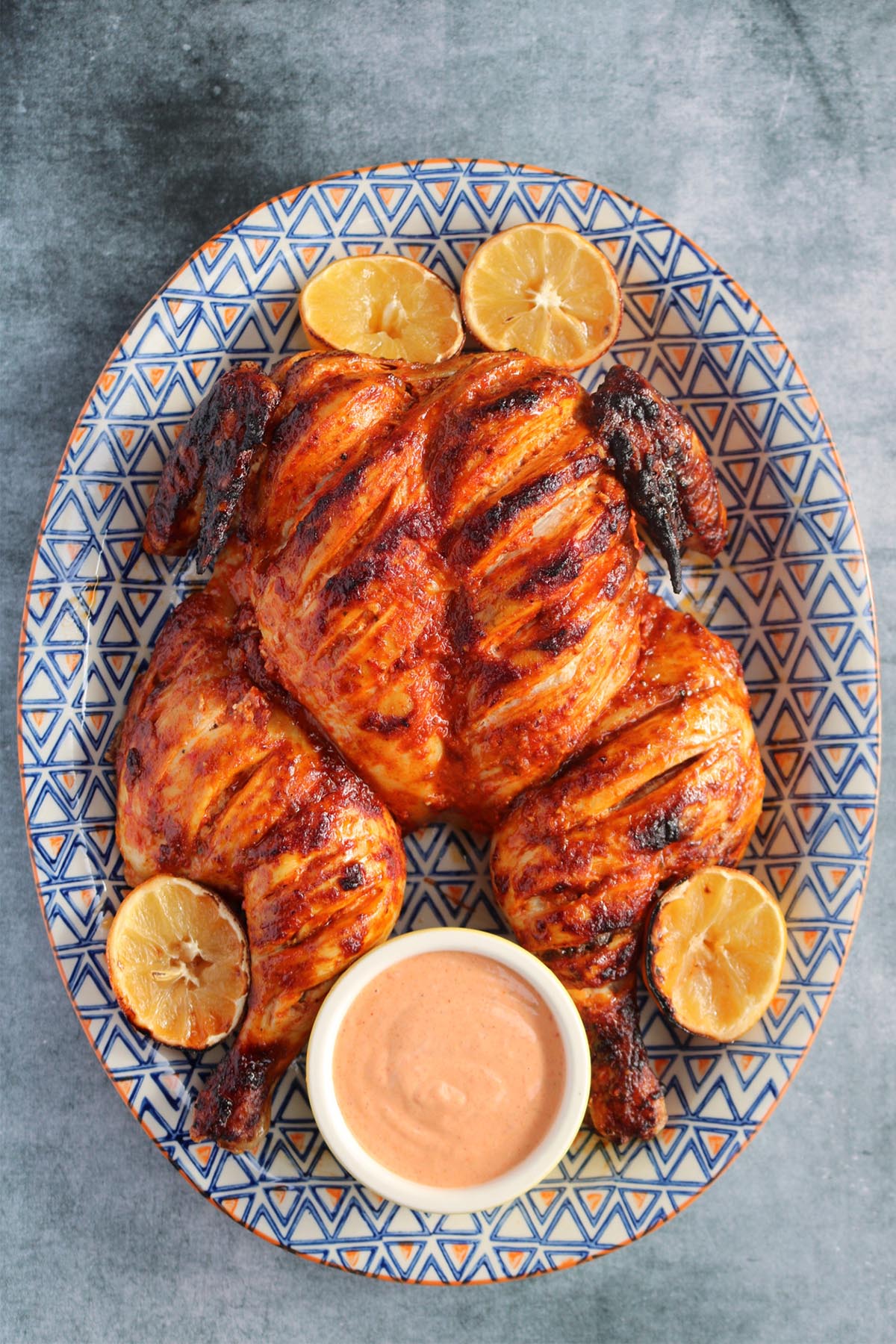 portuguese chicken on large oval serving dish with lemon halves