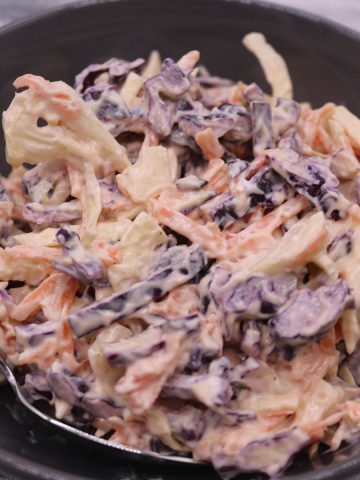 Red and white coleslaw in grey bowl with fork