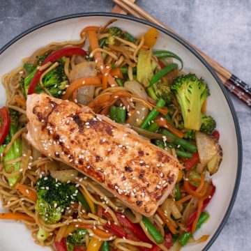 Salmon in a bowl with noodles and vegetables, chopsticks by the side