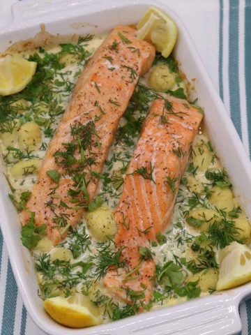 Salmon and gnocchi in rectangle serving dish with lemon wedges