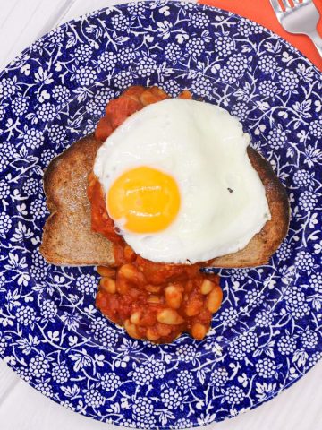 Toast, beans and fried egg on a blue and white plate