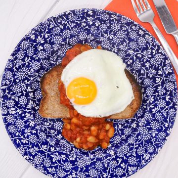 Toast, beans and fried egg on a blue and white plate