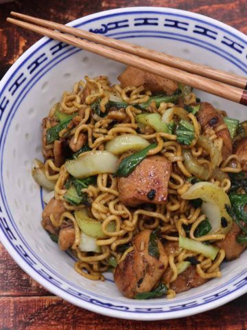 Spicy chicken chow mein in blue and white bowl with chopstickes