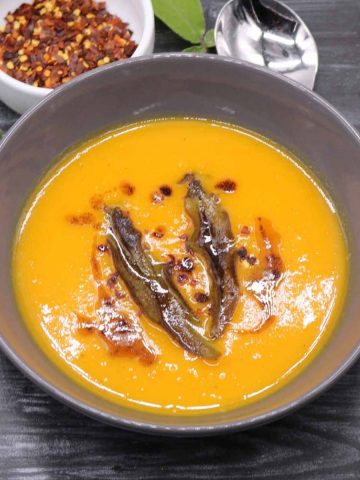 Squash and carrot soup in a grey bowl with crispy sage