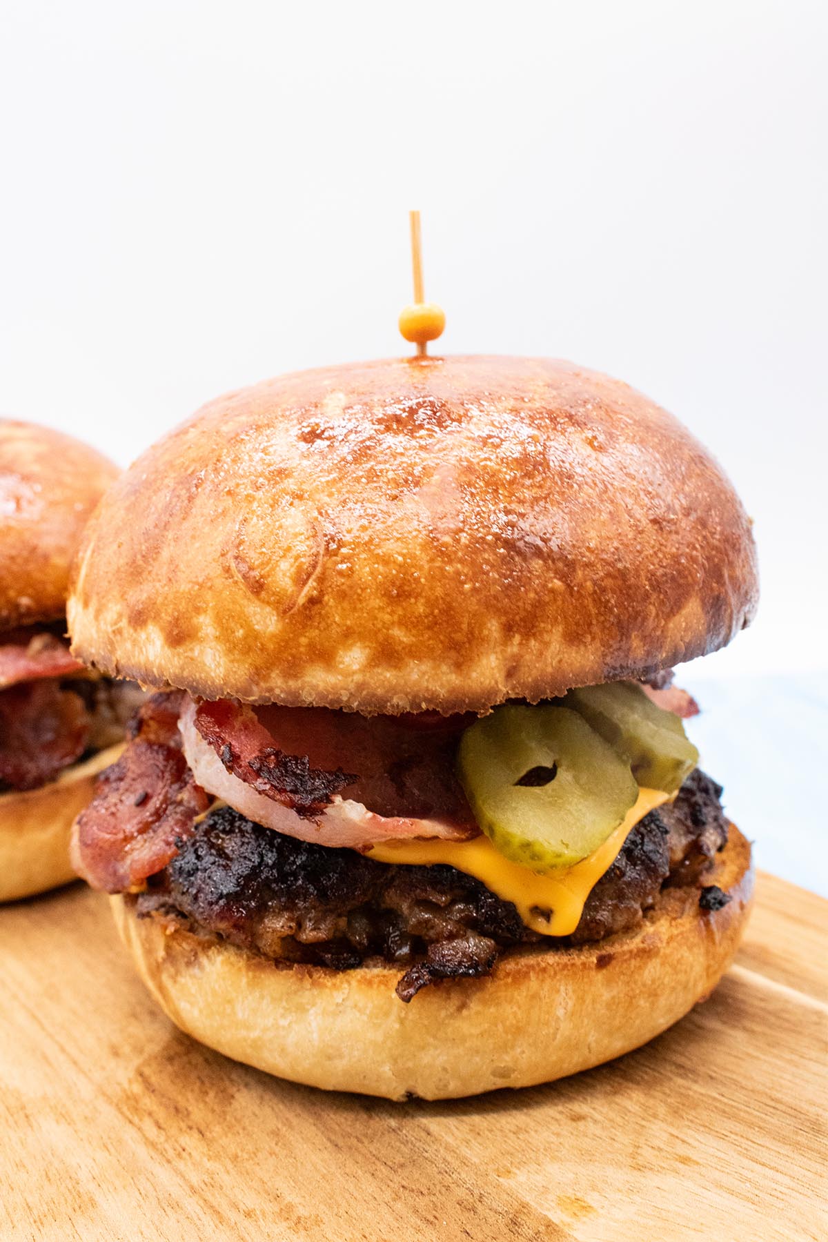 close up of steak and bacon burger in brioche bun on wooded board