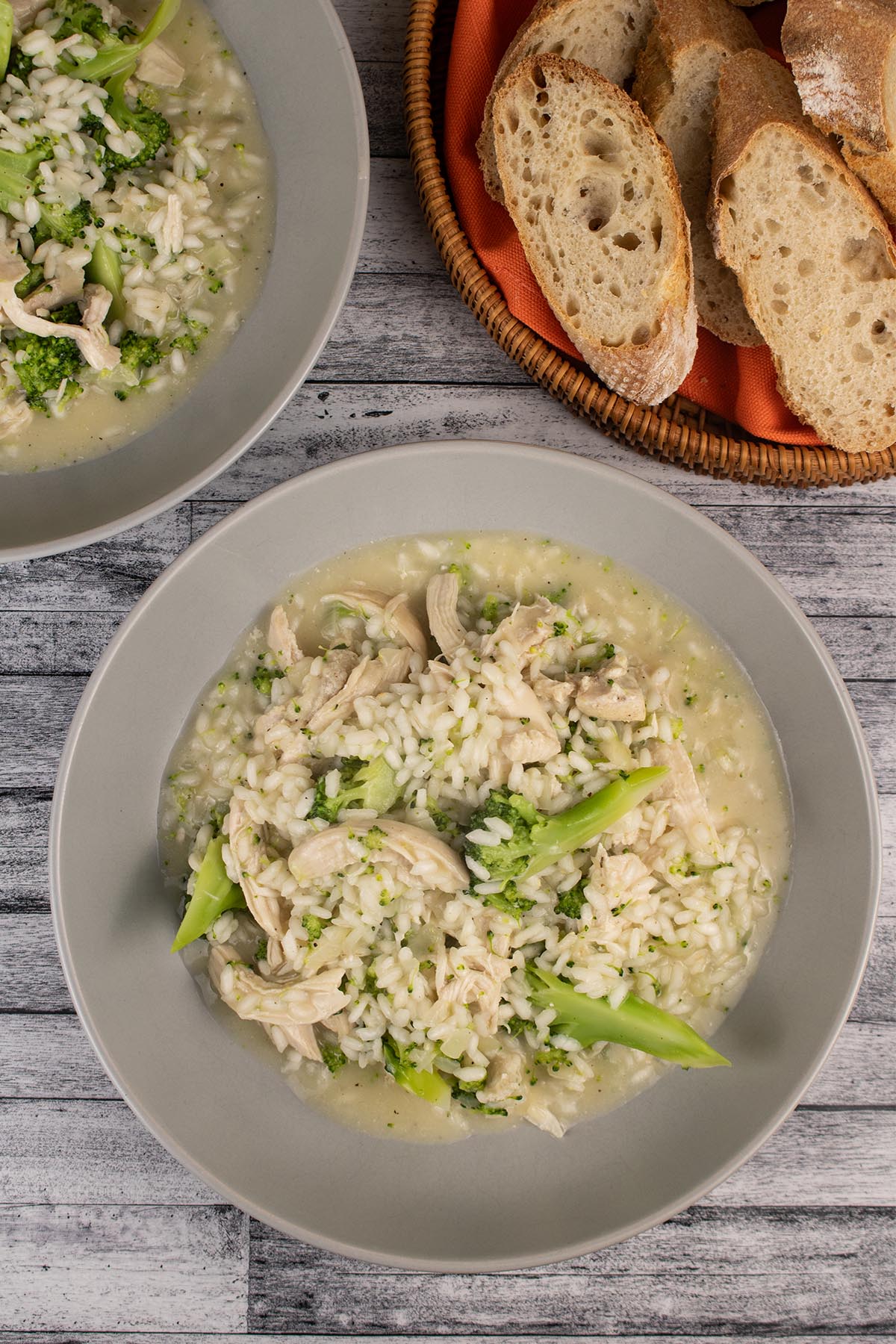 Chicken and broccoli risotto in a grey bowl and sliced baguette