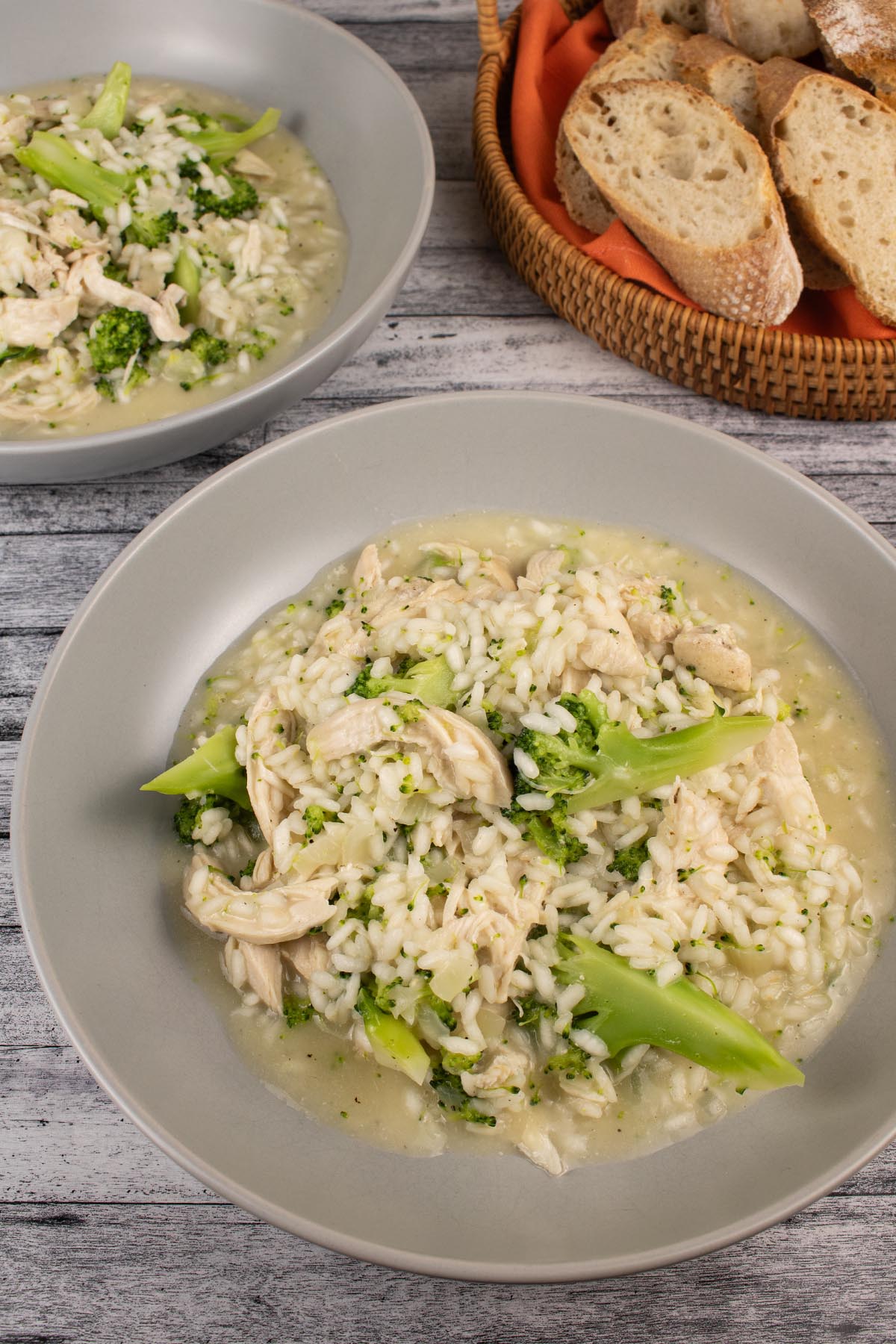 Chicken and broccoli risotto in a grey bowl and sliced baguette