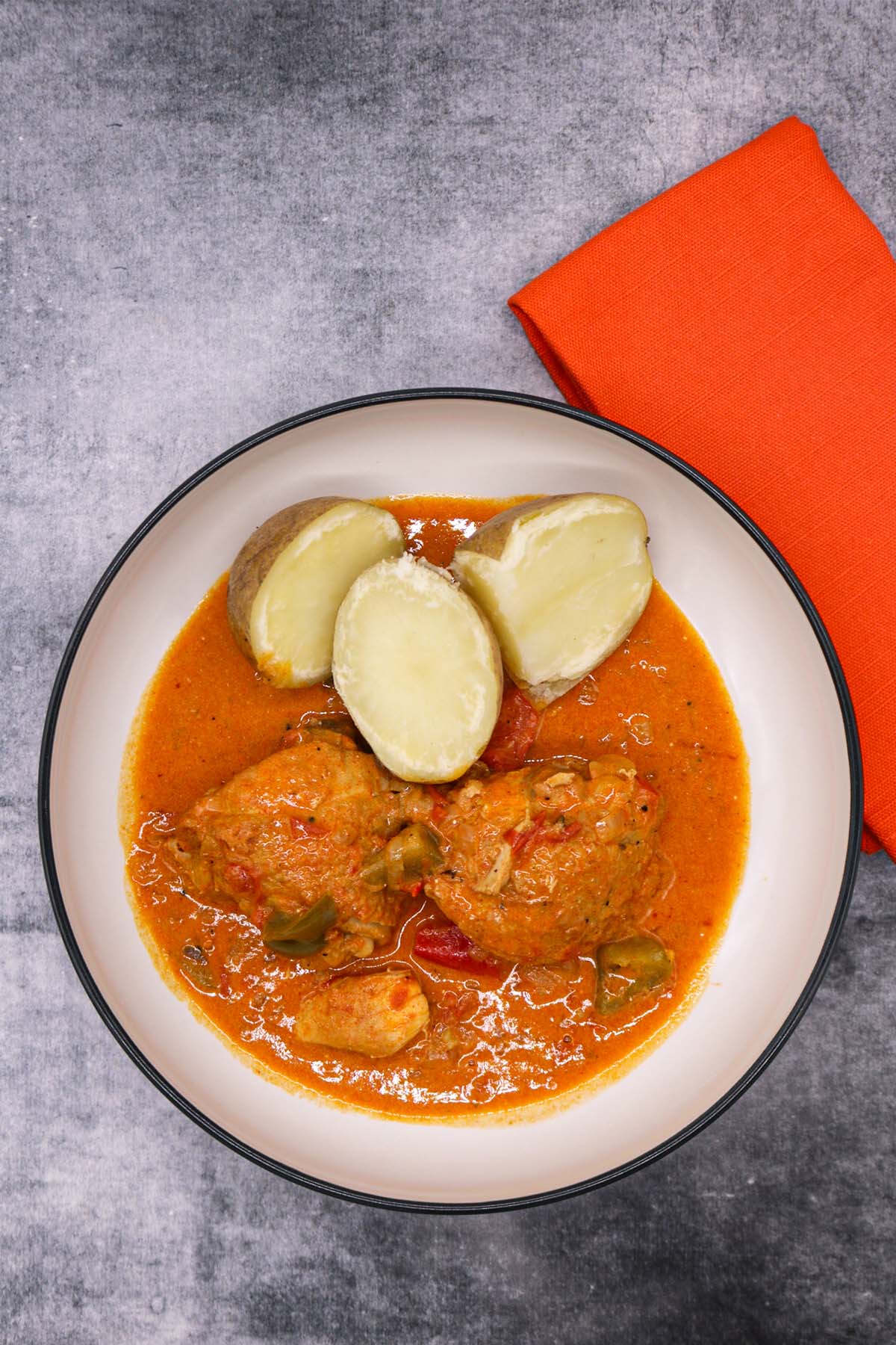 Chicken paprikash in bowl with boiled potatoes