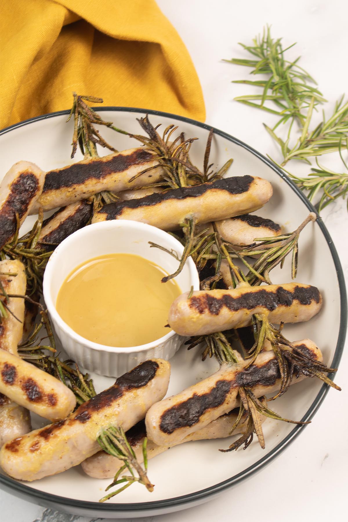 Chipolata rosemary skewers in a bowl with honey mustard dressing