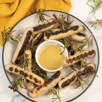 Chipolata rosemary skewers in a bowl with honey mustard dressing