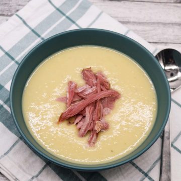 Creamy leek and potato soup in green bowl topped with ham