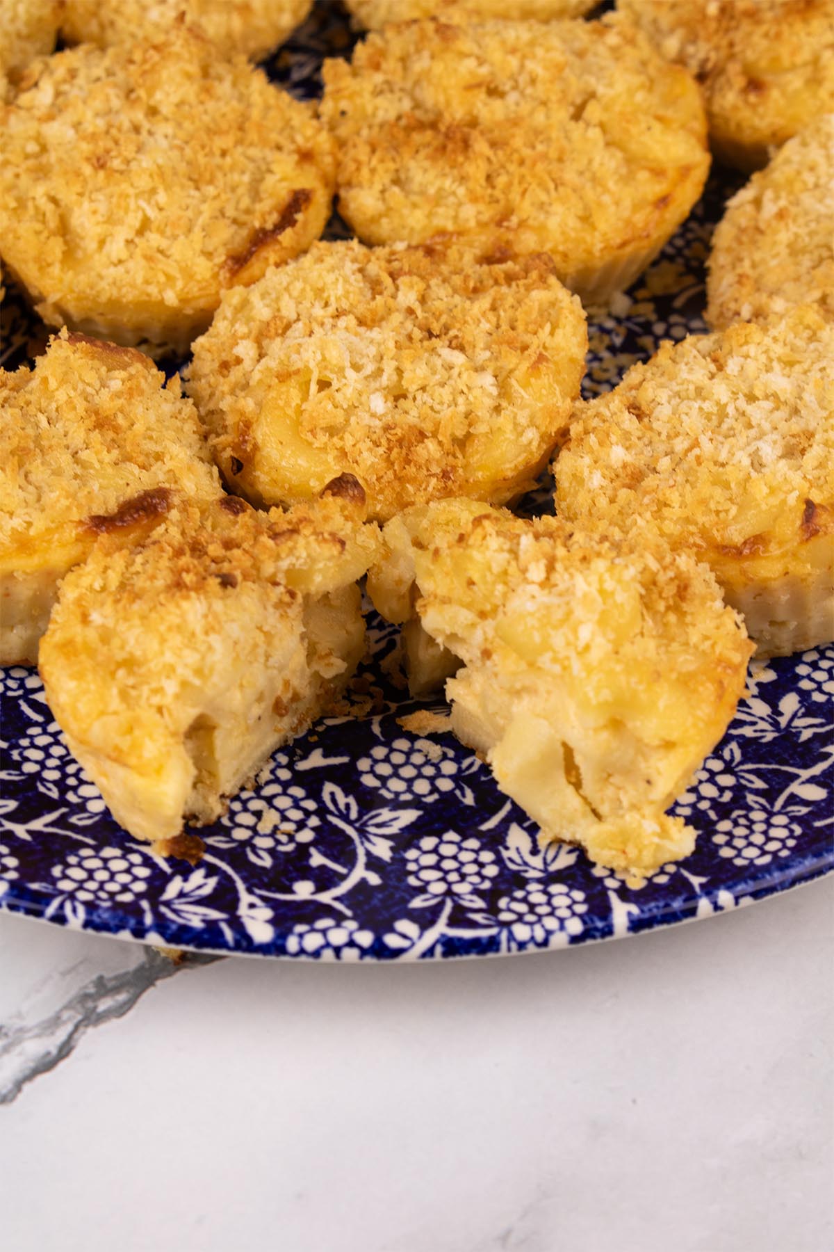 Close up of mac and cheese muffins on blue dinner plate with white berry pattern