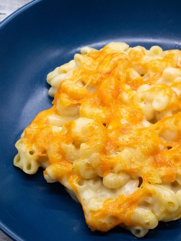 close up of Macaroni cheese in blue round pasta plate