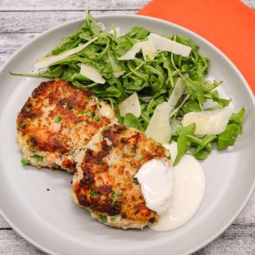 Salmon prawn and pea fish cakes on grey plate with rocket and parmesan salad