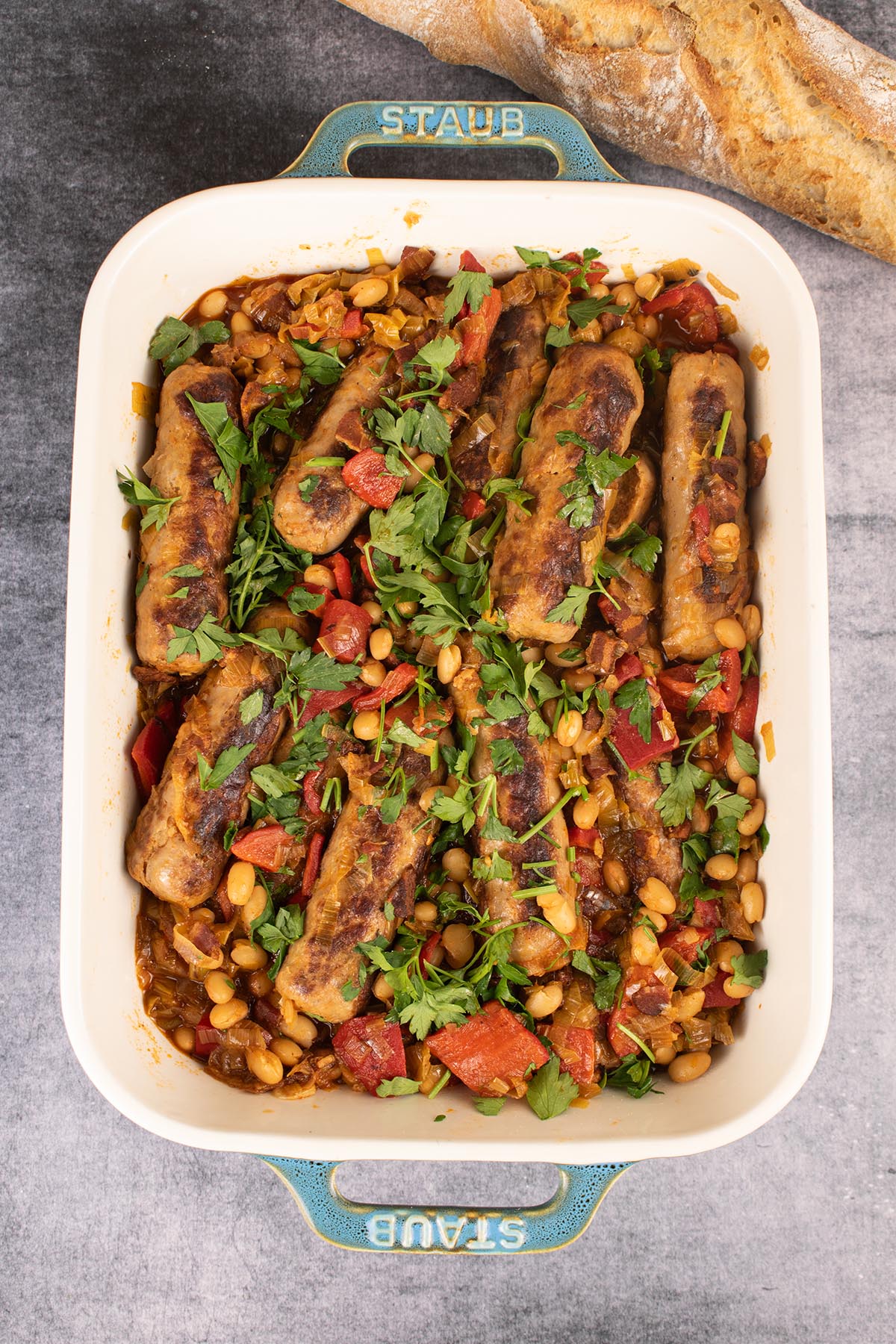 Sausage casserole in rectangle dish with baguette in background