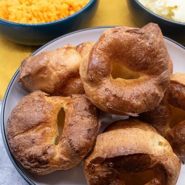 Yorkshire puddings in a white bowl with sides in background