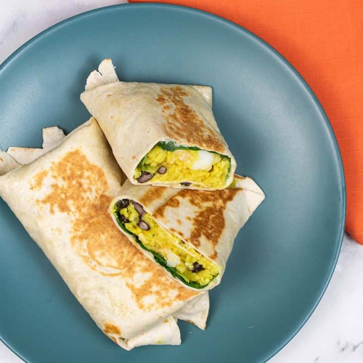 Curried King Prawn Burritos on a teal dinner plate with orange napkin on the side