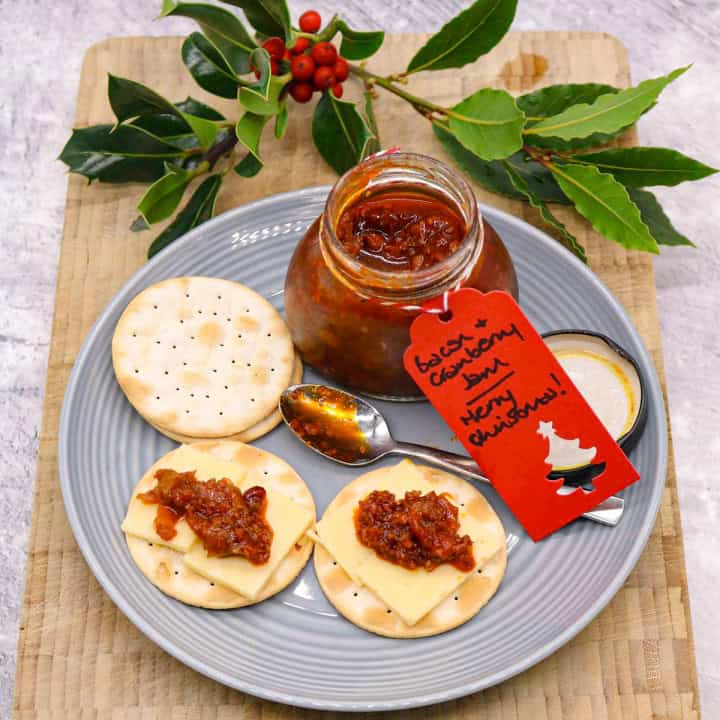 Plate with crackers spread with bacon and cranberry jam and cheese with jar