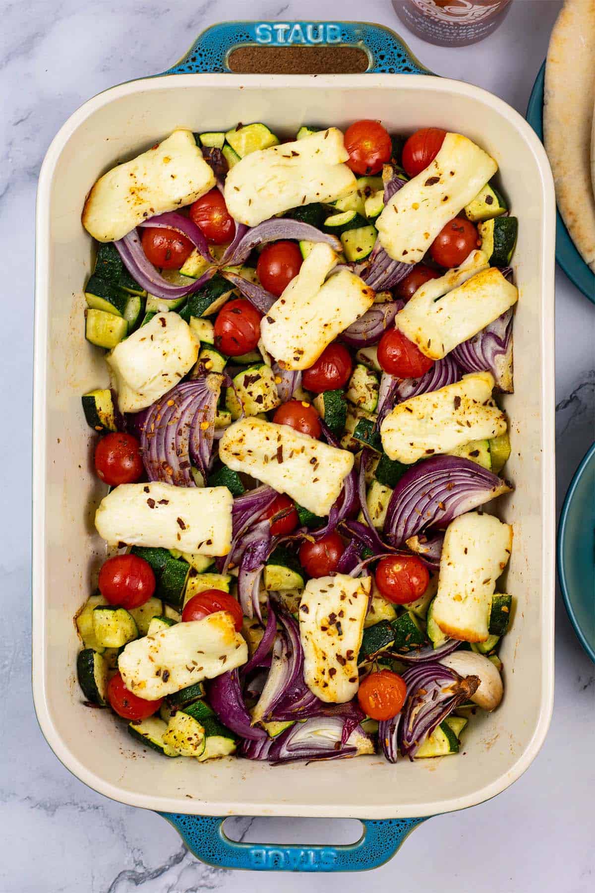 Halloumi and mediterranean veg tray bake in a large rectangle Staub dish.