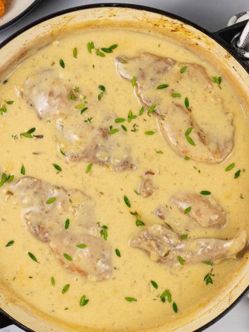 Braised pork steaks with mustard cream sauce in a shallow casserole.