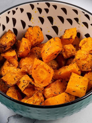 Air fryer carrots and butternut squash in a teal, black and cream patterned bowl.