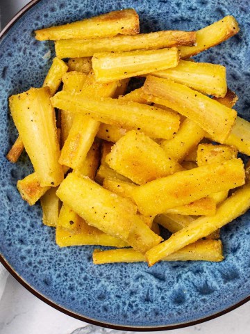 Crisp honey mustard parsnips in a blue patterned serving bowl.