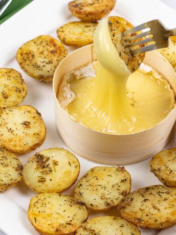 Baked camembert with thyme baby potatoes on a square white platter.