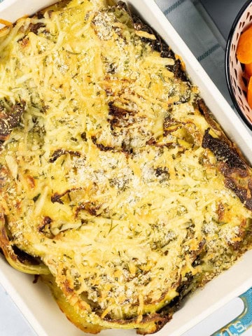 Savoy cabbage gratin with herby cheddar crumbs in a rectangle Staub dish with a bowl of boiled carrots on the side.