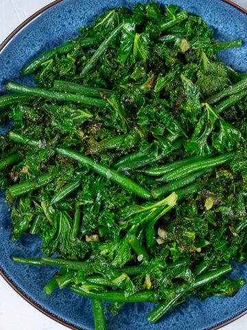 Sautéed kale and green beans in a blue patterned serving bowl.